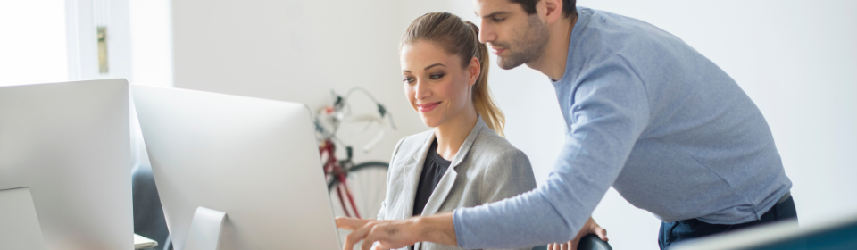 a girl and a guy pointing at a computer in an office